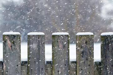 Winter background with a snow-covered wooden fence during a snowfall