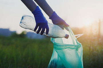 Volunteer young woman collecting trash outside, picking up waste, land pollution and save earth...