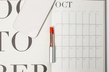 Minimalist and clean Female workspace smart phone , calendar and red lipstick. October