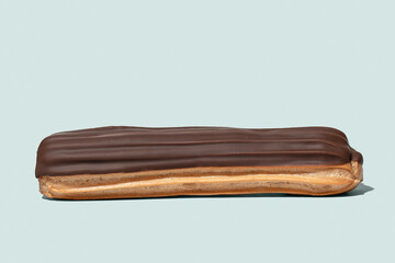 Chocolate eclair on light blue background isolated