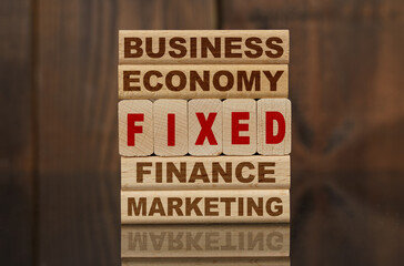 Wooden blocks with the text - Business, Economy, Finance, Marketing and FIXED