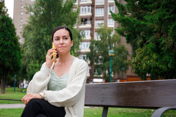 Fototapeta premium Caucasian young woman talking by phone in city park