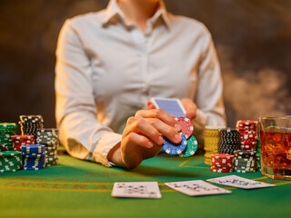 The croupier holds playing cards in his hands. Cards and colored chips are laid out on the green...
