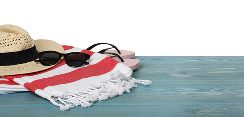 Beach towel, straw hat, flip flops and sunglasses on light blue wooden surface against white background. Space for text