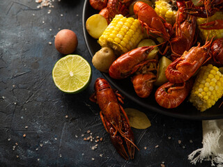 Boiled corn, crayfish, potatoes, lemon. Delicious nutritious dish. Dark background. High angle view. Restaurant, hotel, home cooking, food design.