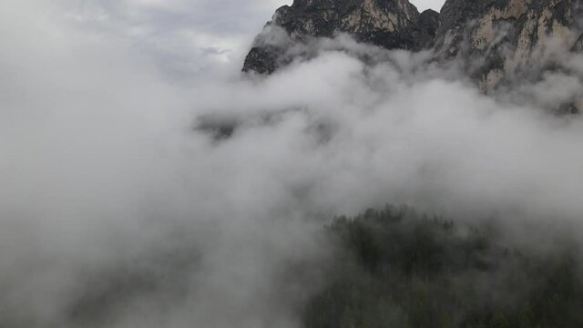 View from the drone to the forest and mountains. Flying over the clouds in the Italian Alps