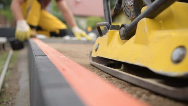 Worker with Soil Compactor Preparing Ground For Paving
