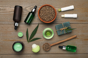 Hemp cosmetics and green leaves on wooden table, flat lay - obrazy, fototapety, plakaty