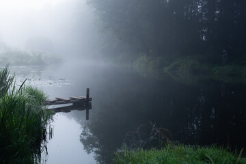 small homemade pier in the village for boats and fishermen on the Fantastic foggy river at the...