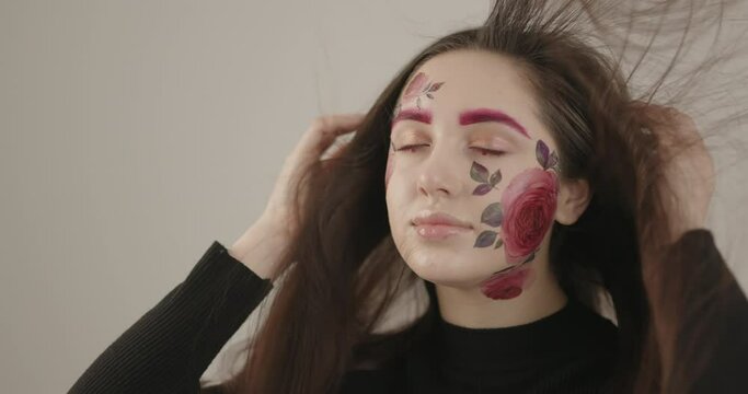 beautiful model posing for the camera in the studio playing with her hair and with a beautifully painted face