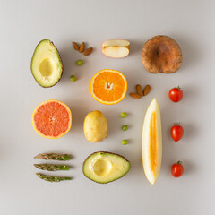 Neatly arranged fresh fruits and vegetables on light gray background.
