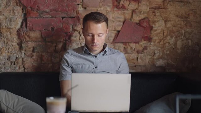 Beautiful Male Developer Or Student Working, Studying By Laptop In Cafe. Freelance, Remote Work, Online Education, Self Employed