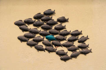 Fototapeta na wymiar A group of decorative fishes on the wall of a house, useful as a background