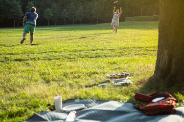 Couple plays with frisbee while waiting for the steak and sausage on the barbecue grill is ready to...