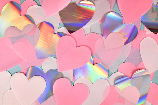 Pink, white and shiny silver colored heart shaped paper confetti on light blue background
