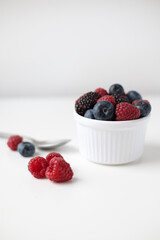 Fresh summer berries on white background with a metallic spoon