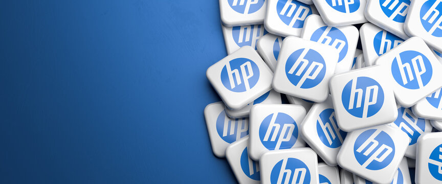 Logos of the computer hardware company Hewlett Packard on a heap on a table. Copy space. Web banner format.