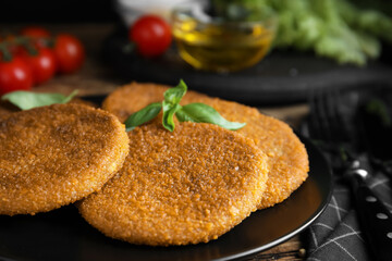 Delicious fried breaded cutlets with basil on wooden table, closeup