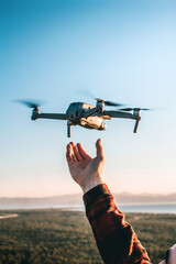 Vertical shot of a person launching a modern drone in a field under the sunlight