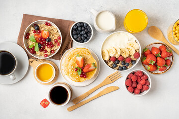 A table for a healthy breakfast of pancakes, granola, fresh berries, coffee with milk and orange juice. Top view.