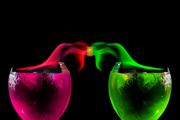 Taças de vidro quebras contendo liquido de cor verde e cor de rosa com chamas das mesmas core se...