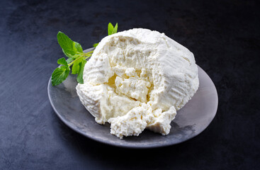 Fresh Italian ricotta with mint leaves served as close-up on a modern design plate
