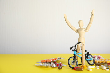 Pills, sportsman and bike model on yellow table, space for text. Using doping in cycling sport...