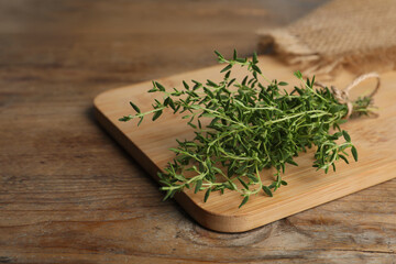 Bunch of aromatic thyme on wooden table, closeup. Space for text