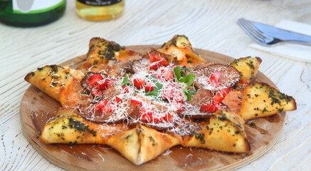 star shaped pizza decorated with pomegranate and cherry tomatoes on wooden board, grey table