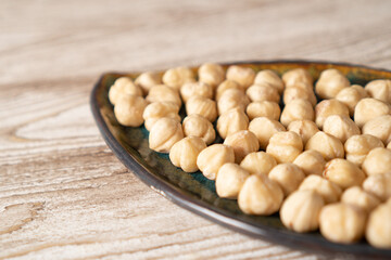 Hazelnuts in bowl. Peeled roasted hazelnut kernels on a plate on wooden table