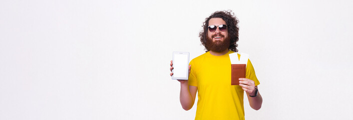 Wide smiling man is showing passport and the screen of the tablet he is holding.