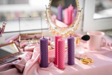 Composition of handmade wax candles. Against background of cosmetics.