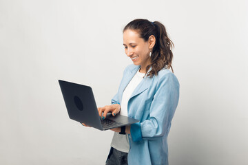 Young business lady is working standing at her laptop in a studio.