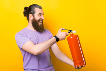 Wide smiling bearded man is holding a fire extinguisher.