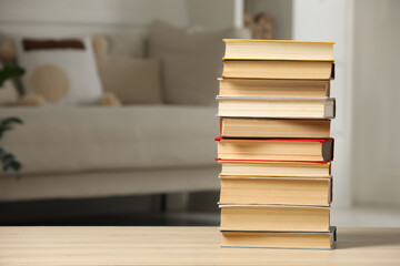 Stack of books on wooden table in living room, space for text. Home library
