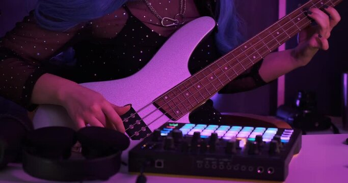 Close-up of bass player tutor rehearsing electronic live performance in the midi controller and bass guitar using in-ear monitoring and headphones and microphone. Backstage acting and rehearsing.