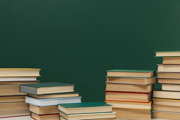 Many hardcover books near green chalkboard, space for text. Library material