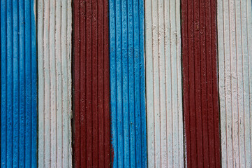 Background of alternating red, blue and white painted planks of an old house
