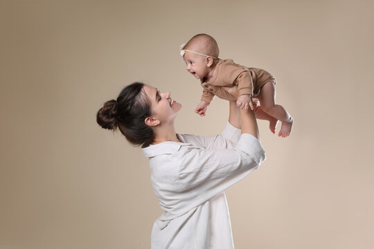 Beautiful mother with her cute baby on beige background