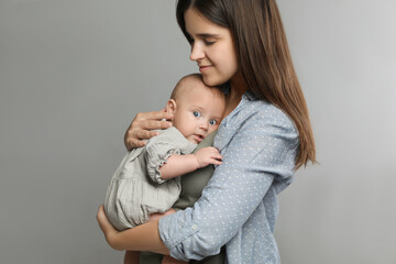 Beautiful mother with her cute baby on grey background