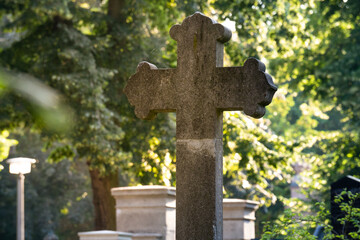 Ein Kreuz auf einem Friedhof bei Sonnenschein. 