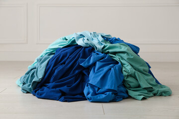 Pile of dirty clothes on floor near light wall indoors