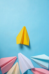 Yellow paper plane leading others on turquoise background, flat lay. Diversity concept