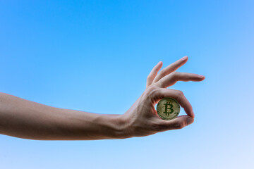 Mano de mujer mostrando un bitcoin con gesto de Ok