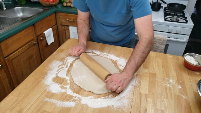 Home cooking - Time lapse of dough being flatten on kitchen wooden table using rolling pin making large pie or pancake to be used to make pierogi.