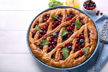Delicious currant pie and fresh berries on white wooden table