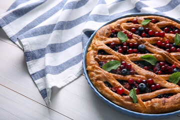 Delicious currant pie and fresh berries on white wooden table