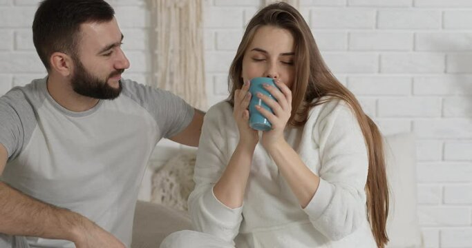 the husband hands his wife a cup of tea and hugs her tightly, enjoying the moment