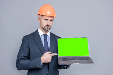 man in helmet pointing finger on green screen. modern wireless laptop. advertisement.