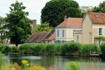 Fototapeta na wymiar Beautiful French village in Burgundy, a rural part of Auxerre city by the river Yonne with lovely houses and relaxing water. Countryside lifestyle in the heart of France.